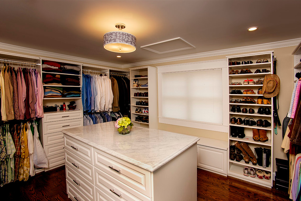 Ejemplo de armario vestidor unisex tradicional grande con armarios con paneles con relieve, puertas de armario blancas y suelo de madera oscura