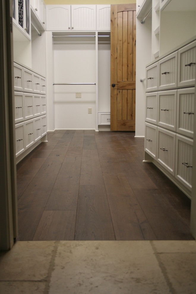 Diseño de armario vestidor tradicional de tamaño medio con suelo de madera oscura y puertas de armario blancas