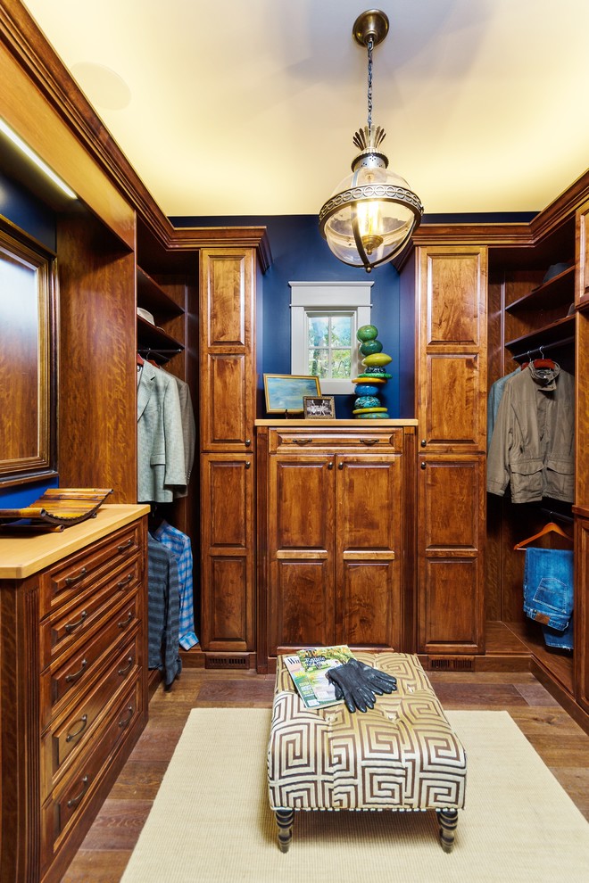 Imagen de armario vestidor de hombre clásico de tamaño medio con armarios con paneles con relieve, puertas de armario de madera oscura y suelo de madera oscura