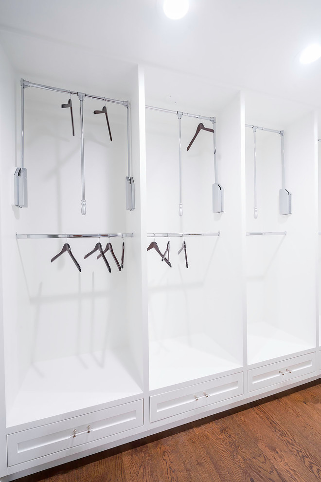 Cette image montre un petit dressing minimaliste neutre avec des portes de placard blanches, parquet clair, un sol marron et un placard à porte shaker.