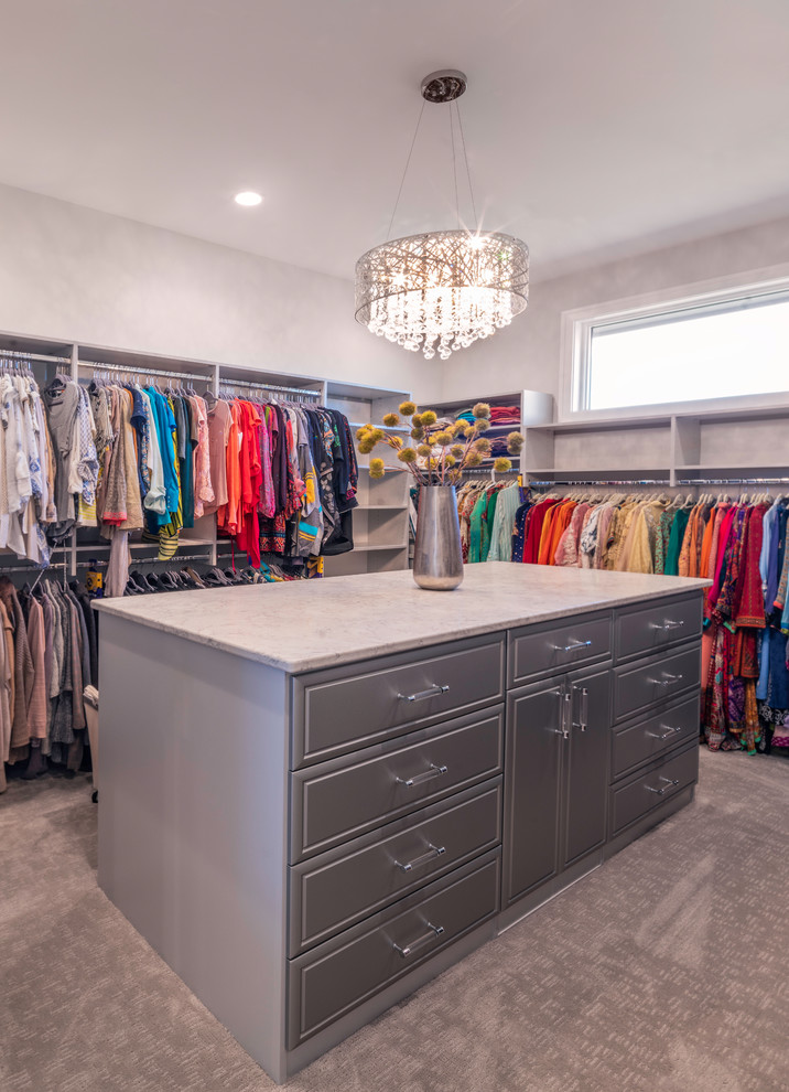 Photo of a large modern walk-in wardrobe for women in Columbus with beaded cabinets, grey cabinets, carpet and grey floors.