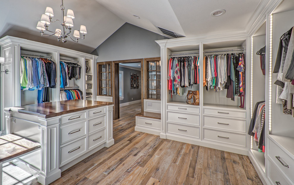 Photo of an expansive classic gender neutral dressing room in Denver with beaded cabinets and medium hardwood flooring.