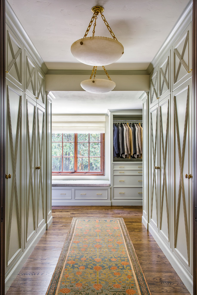 Inspiration pour un grand dressing traditionnel neutre avec un placard à porte affleurante, des portes de placards vertess et un sol en bois brun.