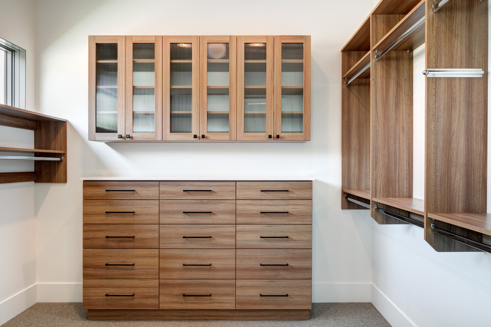 Medium sized contemporary gender neutral walk-in wardrobe in Salt Lake City with glass-front cabinets, light wood cabinets, carpet and grey floors.