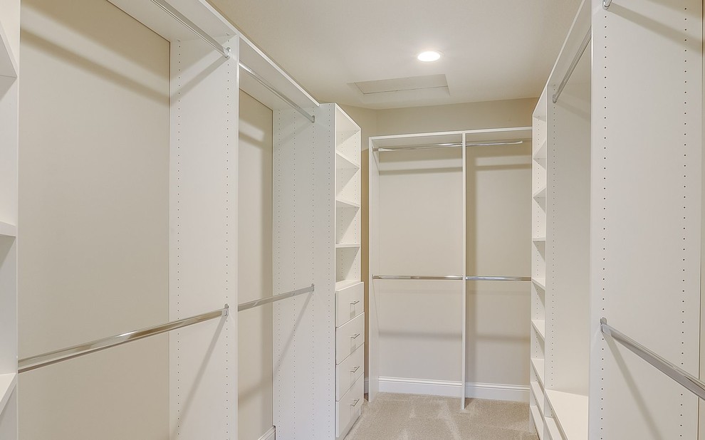 This is an example of a medium sized traditional gender neutral walk-in wardrobe in Minneapolis with white cabinets, carpet and grey floors.