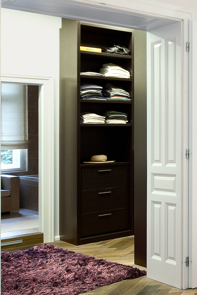 Example of a large transitional gender-neutral medium tone wood floor walk-in closet design in DC Metro with flat-panel cabinets and dark wood cabinets