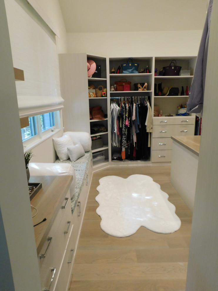 Modelo de armario vestidor abovedado actual grande con armarios abiertos, puertas de armario blancas, suelo de madera en tonos medios y suelo blanco