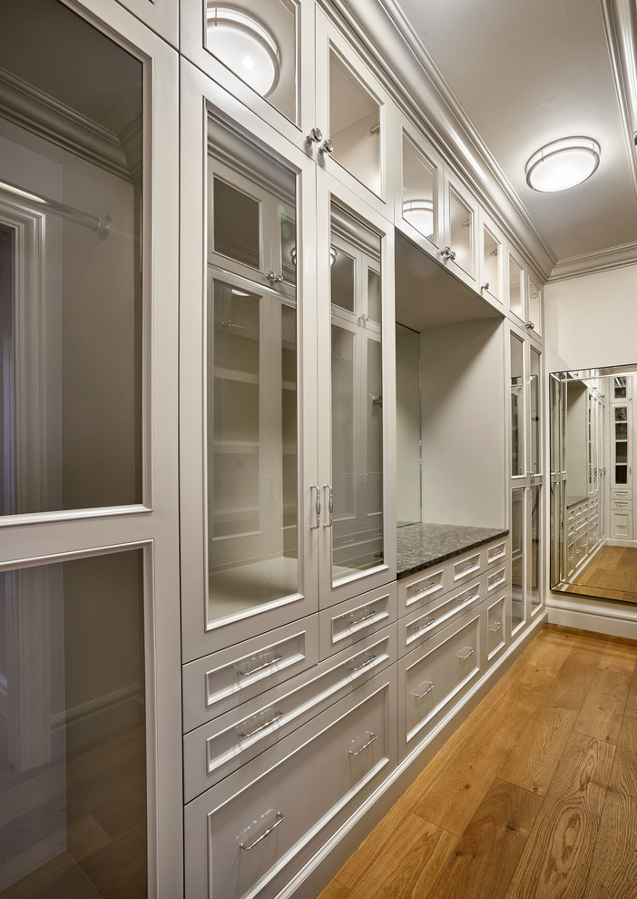 Large elegant gender-neutral medium tone wood floor walk-in closet photo in Portland with glass-front cabinets and gray cabinets