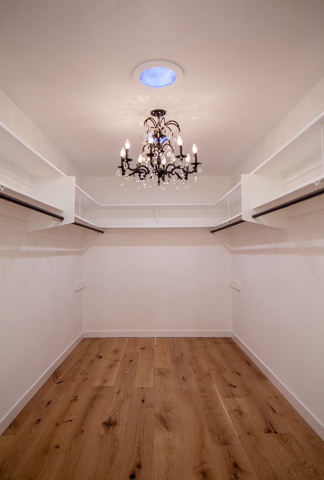 На фото: большая гардеробная комната унисекс в современном стиле с открытыми фасадами, белыми фасадами, светлым паркетным полом и коричневым полом