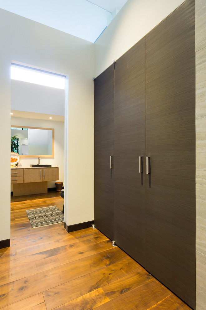 Foto di un ampio armadio o armadio a muro unisex minimal con ante lisce, ante in legno bruno, pavimento in legno massello medio e pavimento marrone