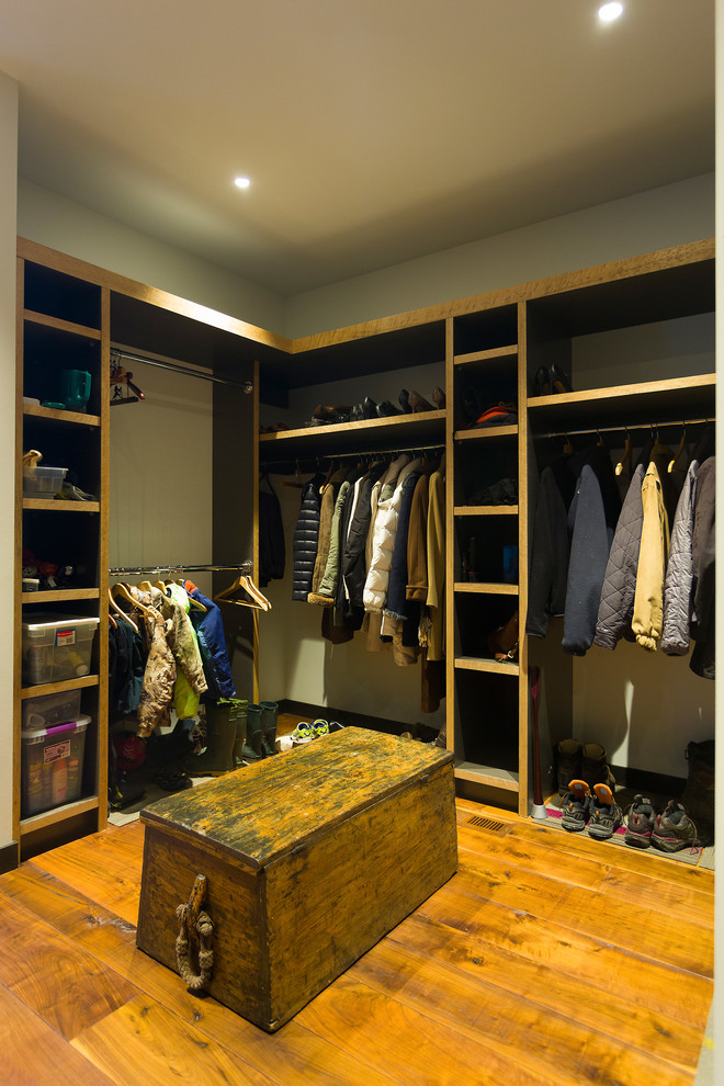 Diseño de vestidor unisex actual extra grande con armarios abiertos, puertas de armario con efecto envejecido, suelo de madera en tonos medios y suelo marrón