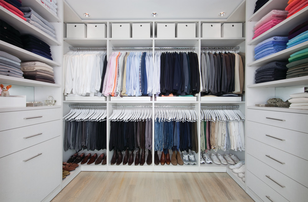 Diseño de armario vestidor unisex minimalista de tamaño medio con armarios con paneles lisos, puertas de armario blancas y suelo de madera clara