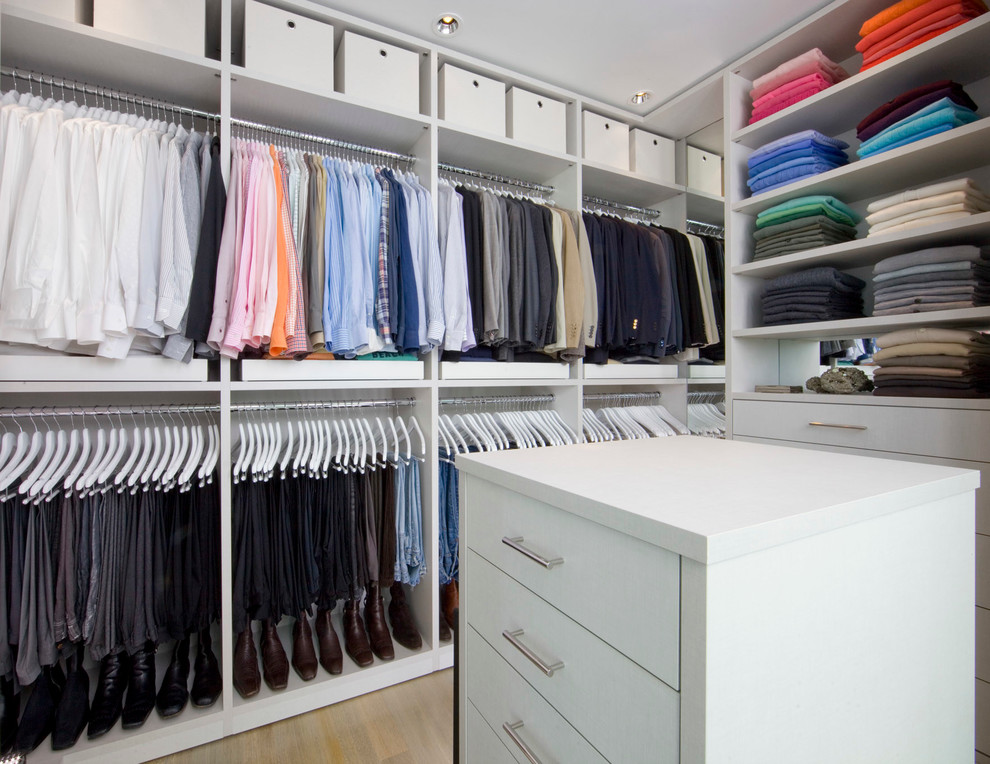 Modelo de armario vestidor unisex actual con armarios con paneles lisos, suelo de madera clara y puertas de armario blancas