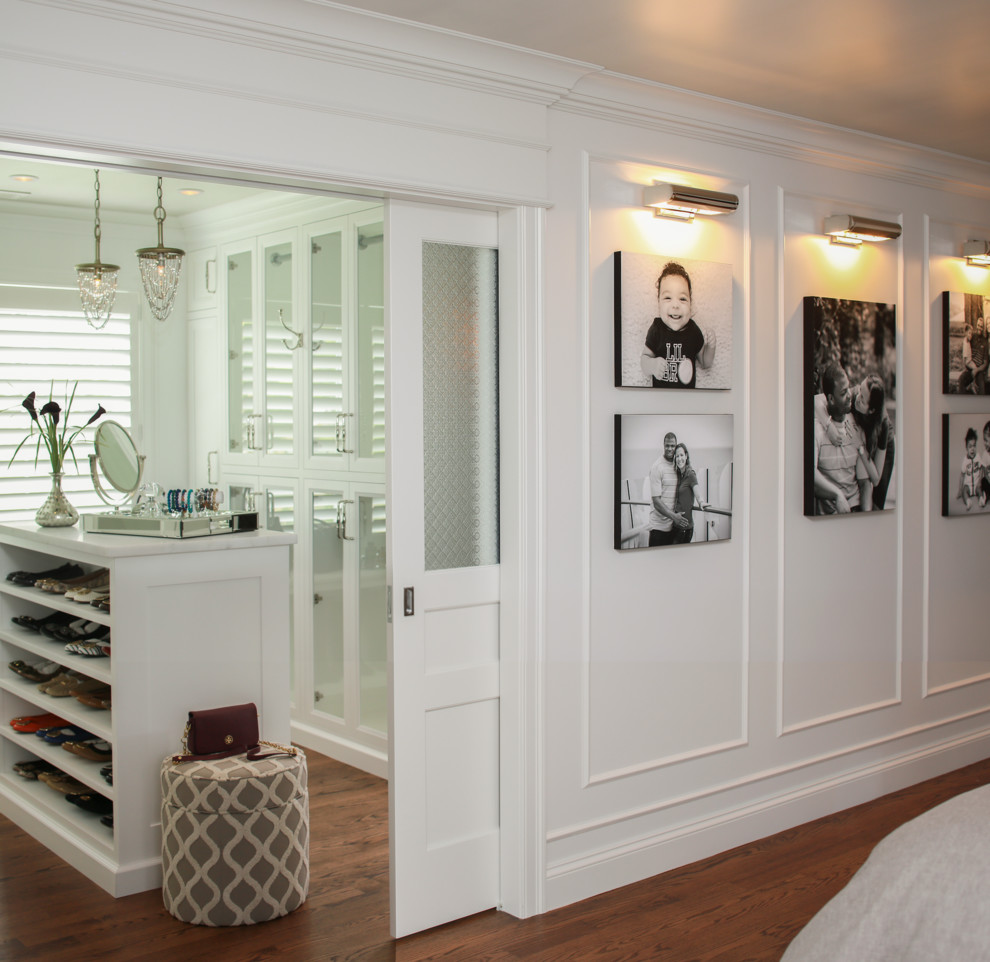 Großer, Neutraler Klassischer Begehbarer Kleiderschrank mit Glasfronten, weißen Schränken und braunem Holzboden in New York