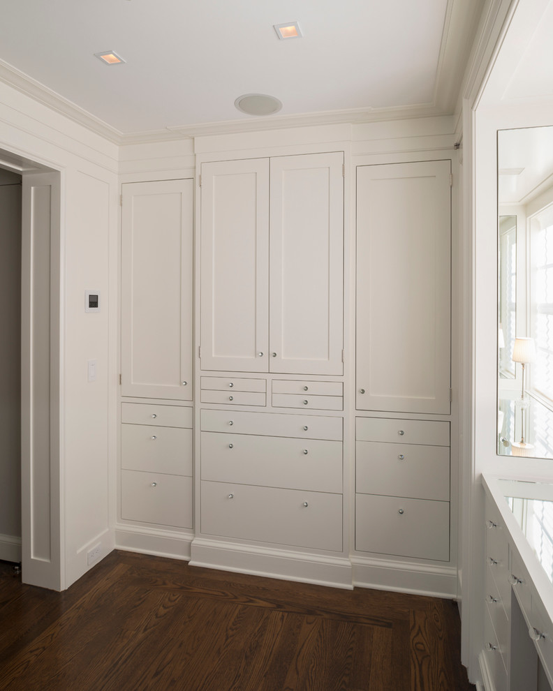 Пример оригинального дизайна: большая гардеробная комната в современном стиле с фасадами с утопленной филенкой, белыми фасадами и паркетным полом среднего тона