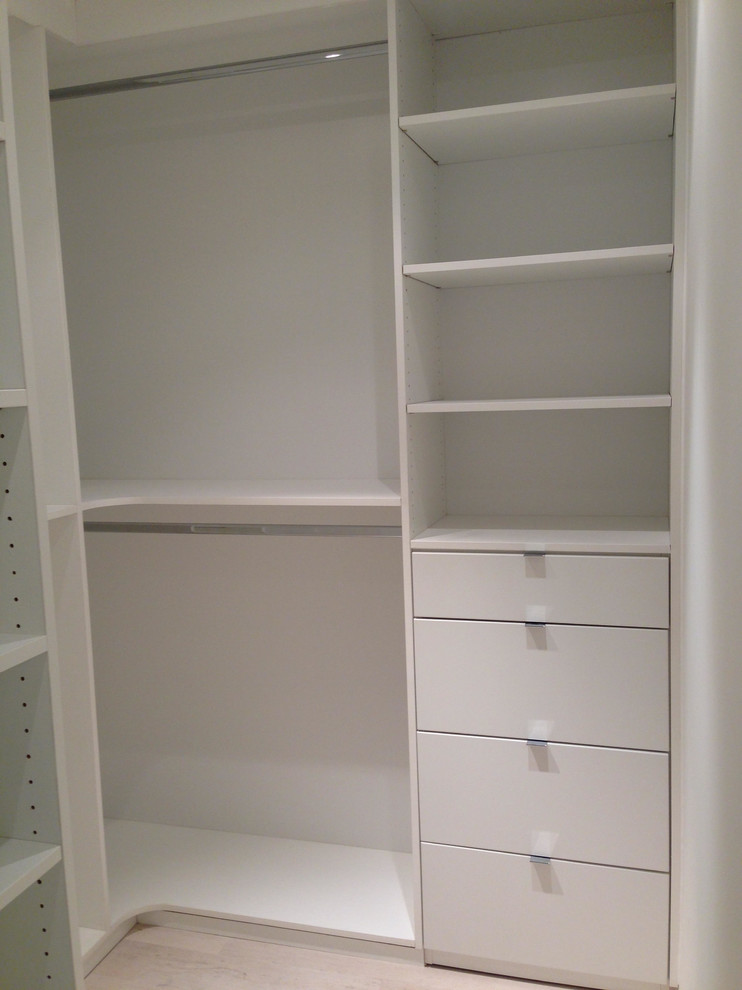 Imagen de armario vestidor unisex minimalista grande con armarios con paneles lisos, puertas de armario blancas, suelo de baldosas de porcelana y suelo beige