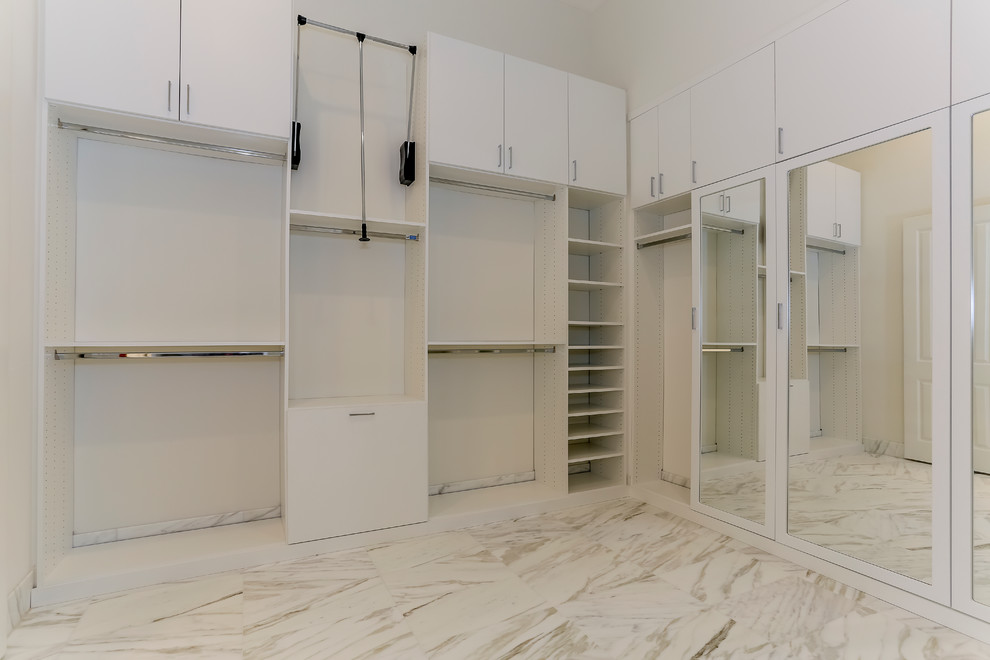 Diseño de armario vestidor unisex actual grande con armarios con paneles lisos, puertas de armario blancas, suelo de mármol y suelo beige