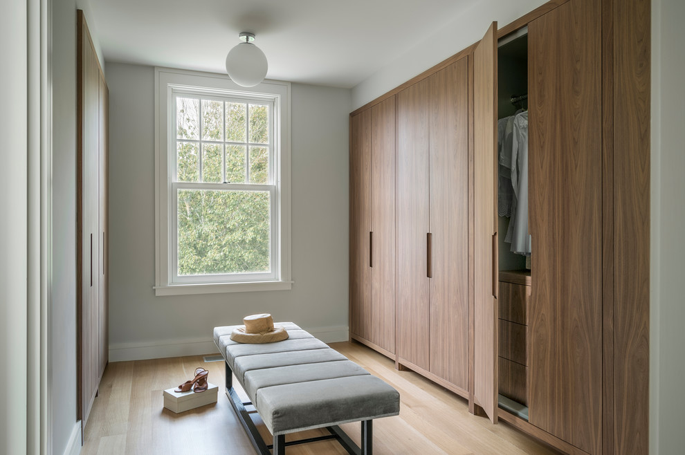 Ejemplo de armario vestidor unisex contemporáneo grande con armarios con paneles lisos, puertas de armario de madera oscura, suelo de madera clara y suelo marrón