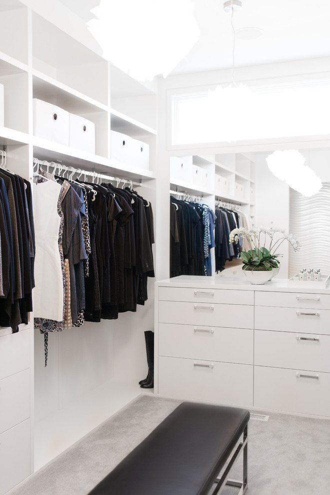 This is an example of a contemporary gender neutral walk-in wardrobe in Calgary with flat-panel cabinets, white cabinets, carpet and grey floors.