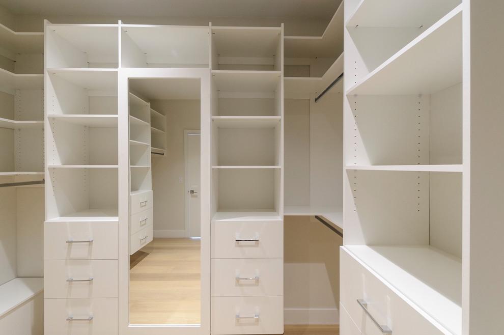 Imagen de armario vestidor clásico renovado grande con armarios abiertos, puertas de armario blancas y suelo de madera clara