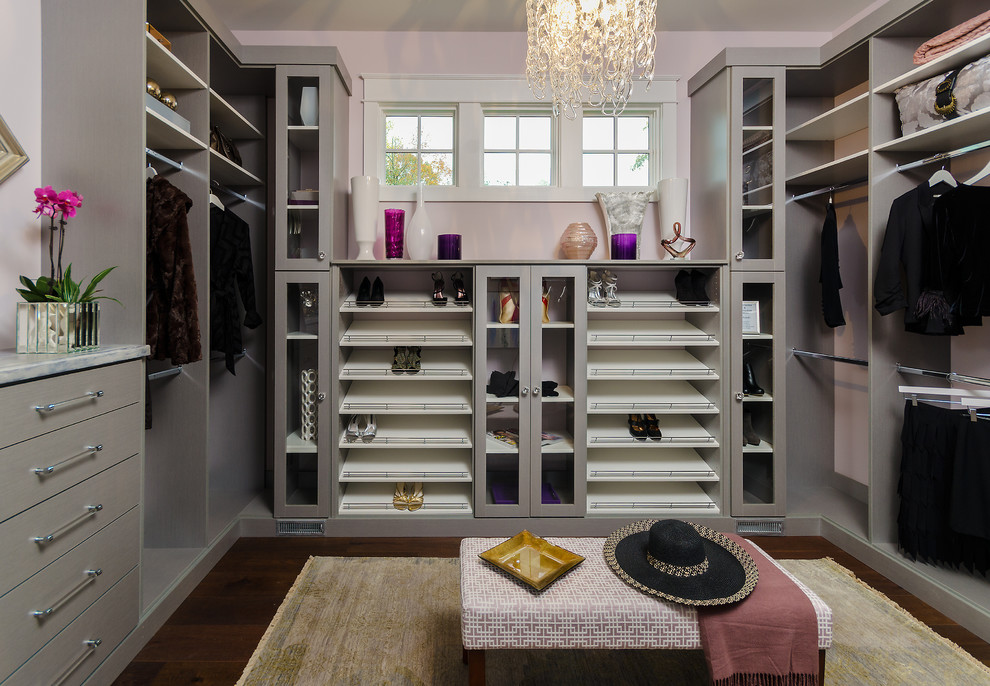 Réalisation d'un grand dressing room tradition pour une femme avec des portes de placard grises, parquet foncé, un sol marron et un placard sans porte.