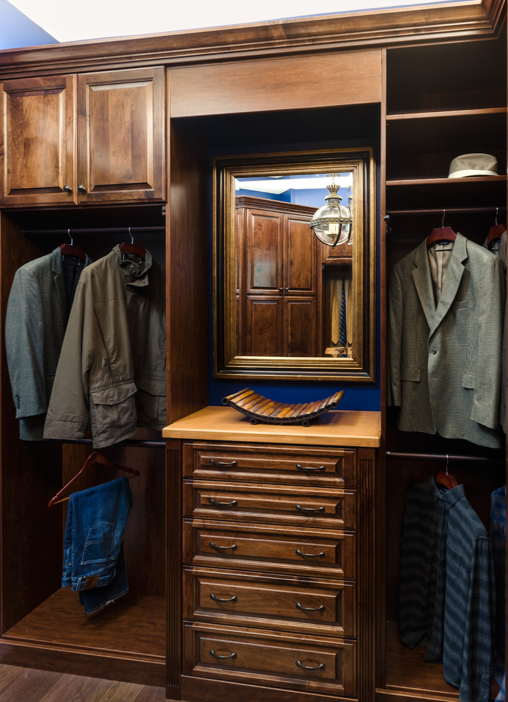 Immagine di uno spazio per vestirsi per uomo classico di medie dimensioni con ante con bugna sagomata, ante in legno bruno e parquet scuro