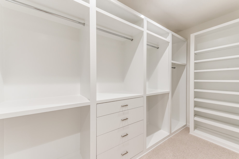 Ejemplo de armario vestidor unisex actual de tamaño medio con armarios con paneles lisos, puertas de armario blancas, moqueta y suelo beige