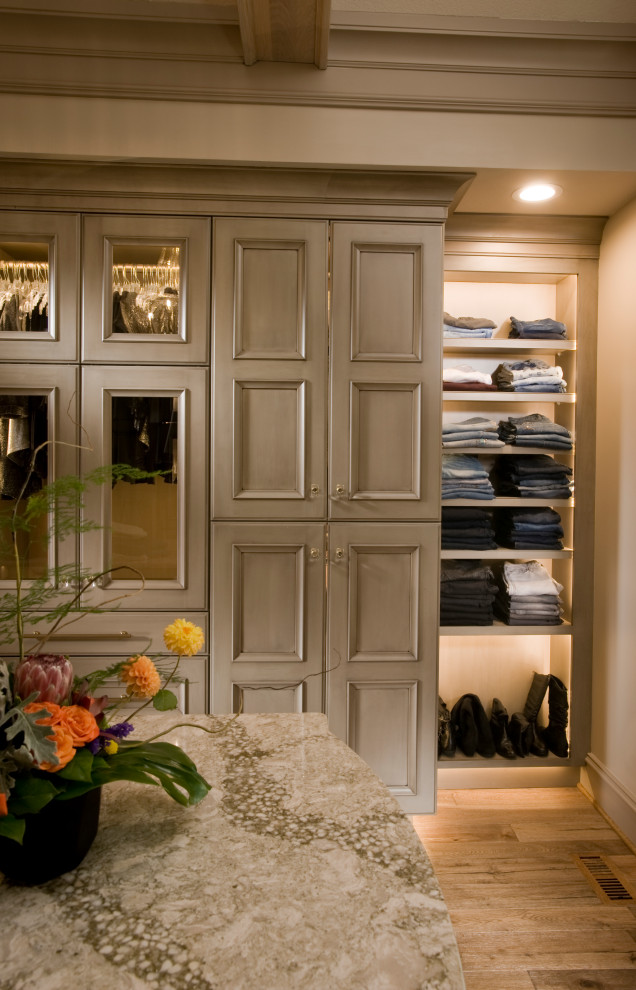 Exemple d'un grand dressing room chic neutre avec un placard avec porte à panneau encastré, des portes de placard beiges, un sol en bois brun et un sol marron.