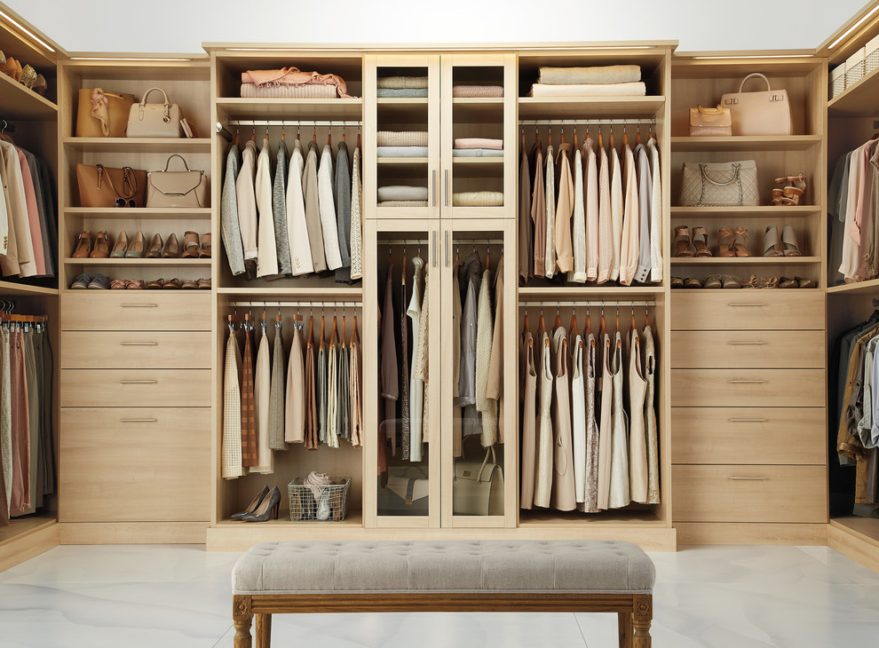 Modelo de armario vestidor de mujer actual con armarios con paneles lisos, puertas de armario de madera clara y suelo de mármol