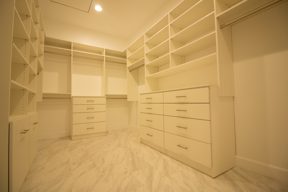 Example of a large trendy gender-neutral marble floor and gray floor walk-in closet design in Phoenix with flat-panel cabinets and white cabinets