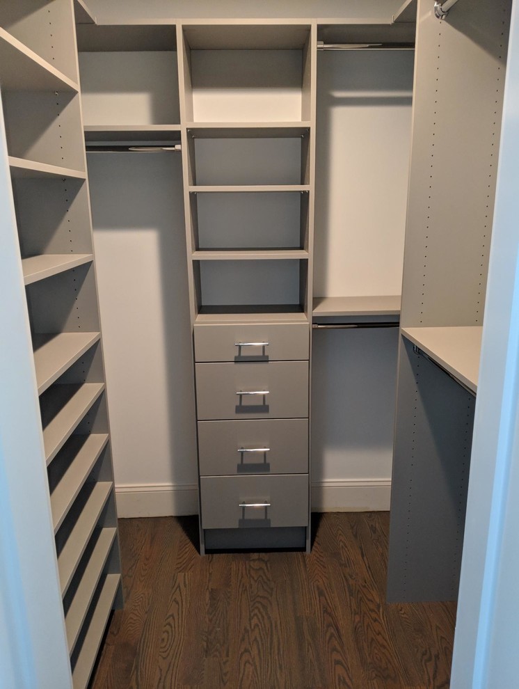 This is an example of a small classic walk-in wardrobe in New York with flat-panel cabinets, grey cabinets, dark hardwood flooring and brown floors.