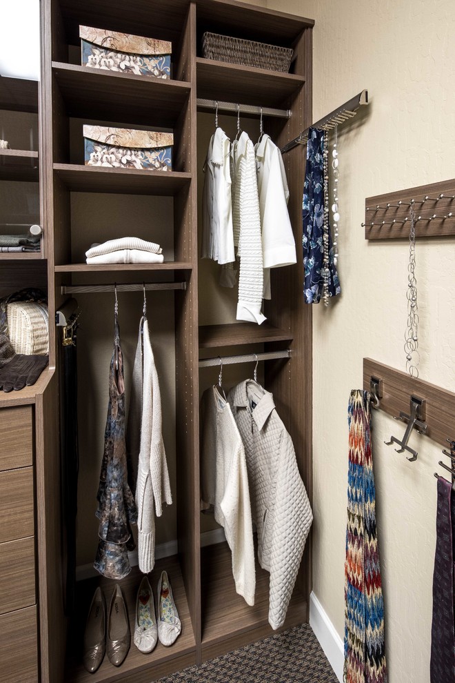 Example of a small trendy gender-neutral carpeted reach-in closet design in San Francisco with glass-front cabinets and medium tone wood cabinets