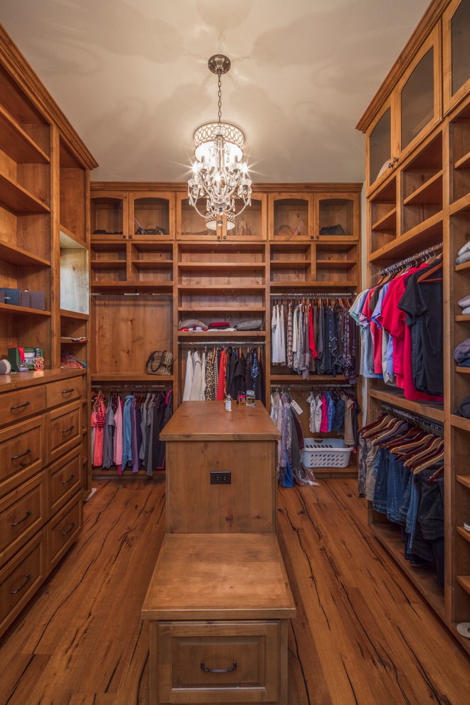 This is an example of a large mediterranean walk-in wardrobe for women in Austin with raised-panel cabinets, light wood cabinets and light hardwood flooring.