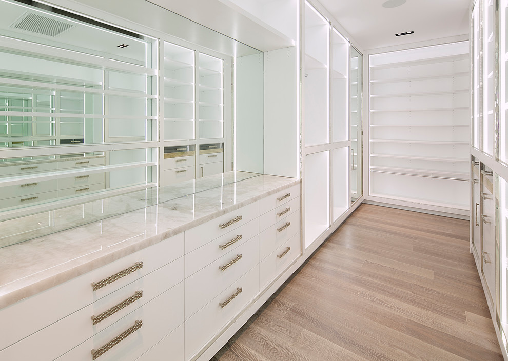 Inspiration for a large contemporary gender neutral walk-in wardrobe in Los Angeles with flat-panel cabinets, white cabinets, light hardwood flooring and brown floors.