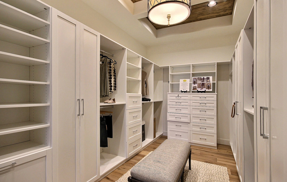 Modelo de armario vestidor unisex campestre extra grande con armarios con paneles empotrados, puertas de armario blancas, suelo de madera clara y suelo marrón