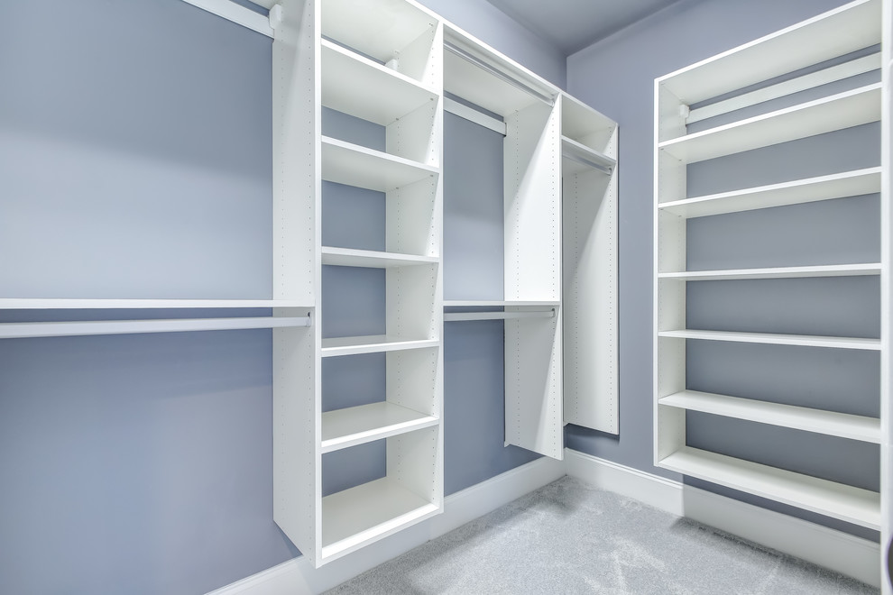 This is an example of a medium sized classic gender neutral walk-in wardrobe in Other with open cabinets, white cabinets and carpet.