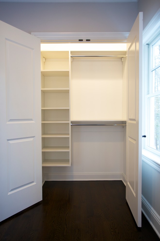 Photo of a small classic gender neutral standard wardrobe in New York with open cabinets, white cabinets, dark hardwood flooring and brown floors.