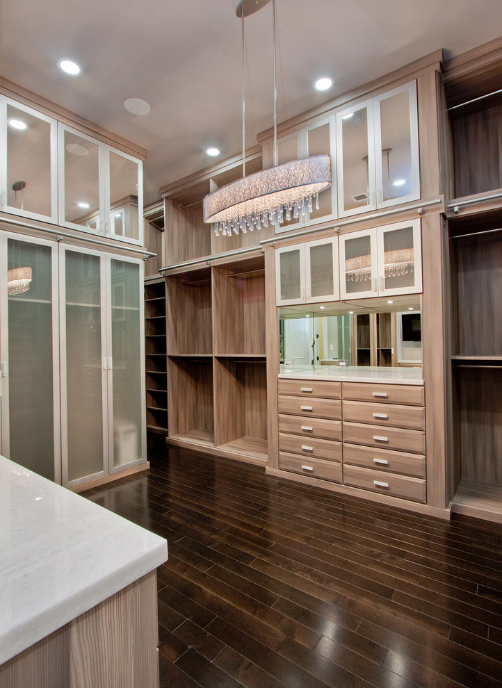 Expansive classic walk-in wardrobe for women in Miami with raised-panel cabinets, dark wood cabinets and dark hardwood flooring.