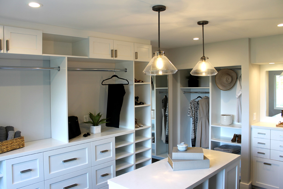 Expansive modern gender neutral walk-in wardrobe in Los Angeles with recessed-panel cabinets, white cabinets, carpet and grey floors.