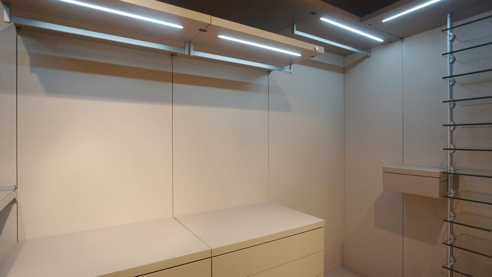 Idee per una cabina armadio per uomo minimalista di medie dimensioni con ante lisce, parquet scuro e ante bianche