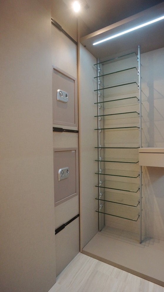 Modelo de armario vestidor de hombre minimalista de tamaño medio con armarios con paneles lisos, suelo de madera oscura y puertas de armario blancas