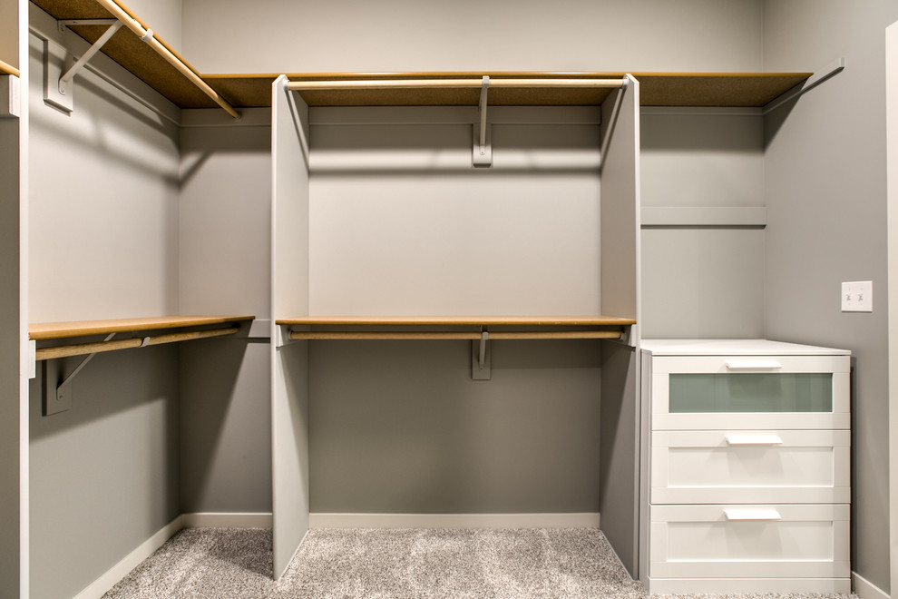 This is an example of a large contemporary gender neutral walk-in wardrobe in Other with carpet and beige floors.