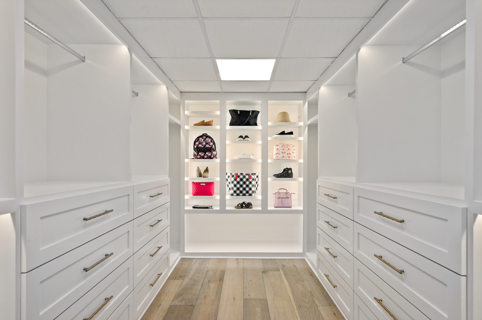 Modelo de armario vestidor unisex minimalista grande con armarios con paneles con relieve, puertas de armario blancas, suelo de madera clara y suelo marrón