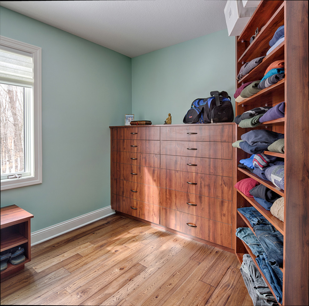 Diseño de armario y vestidor clásico renovado con suelo de madera en tonos medios y puertas de armario de madera oscura