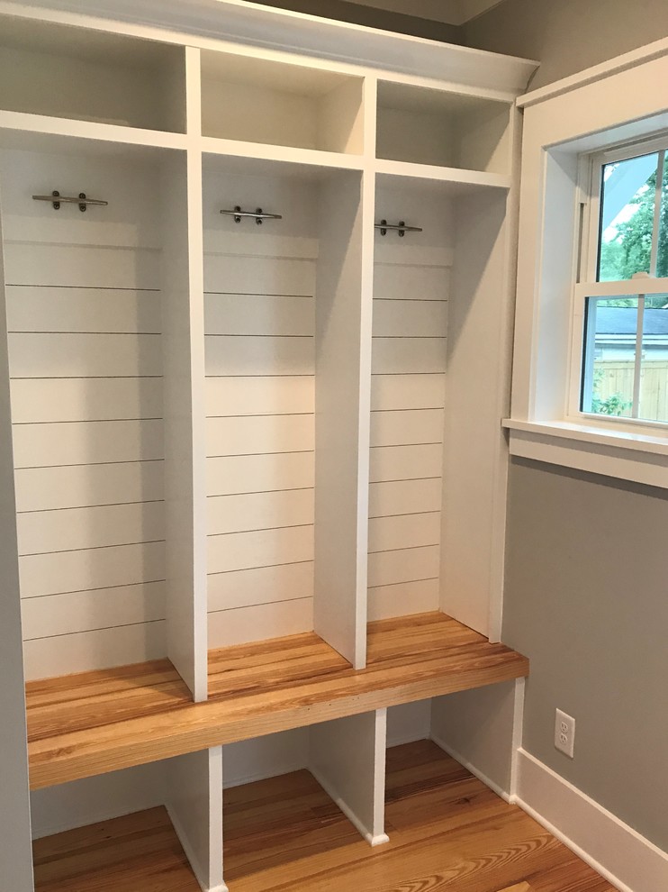 Medium sized coastal walk-in wardrobe in Charleston with beaded cabinets, white cabinets and medium hardwood flooring.