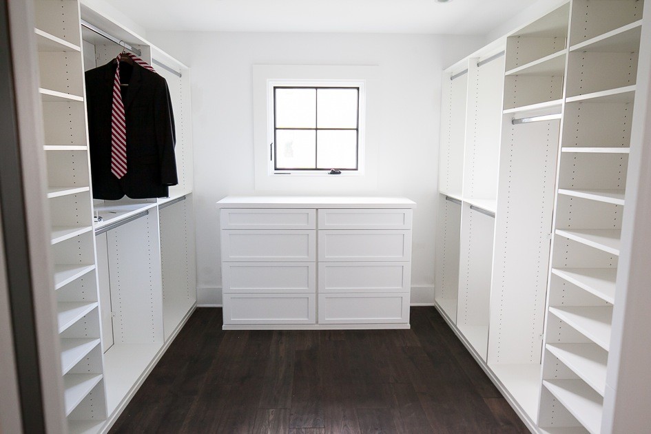 Modelo de armario vestidor unisex campestre de tamaño medio con puertas de armario blancas, armarios con paneles empotrados, suelo de madera oscura y suelo marrón