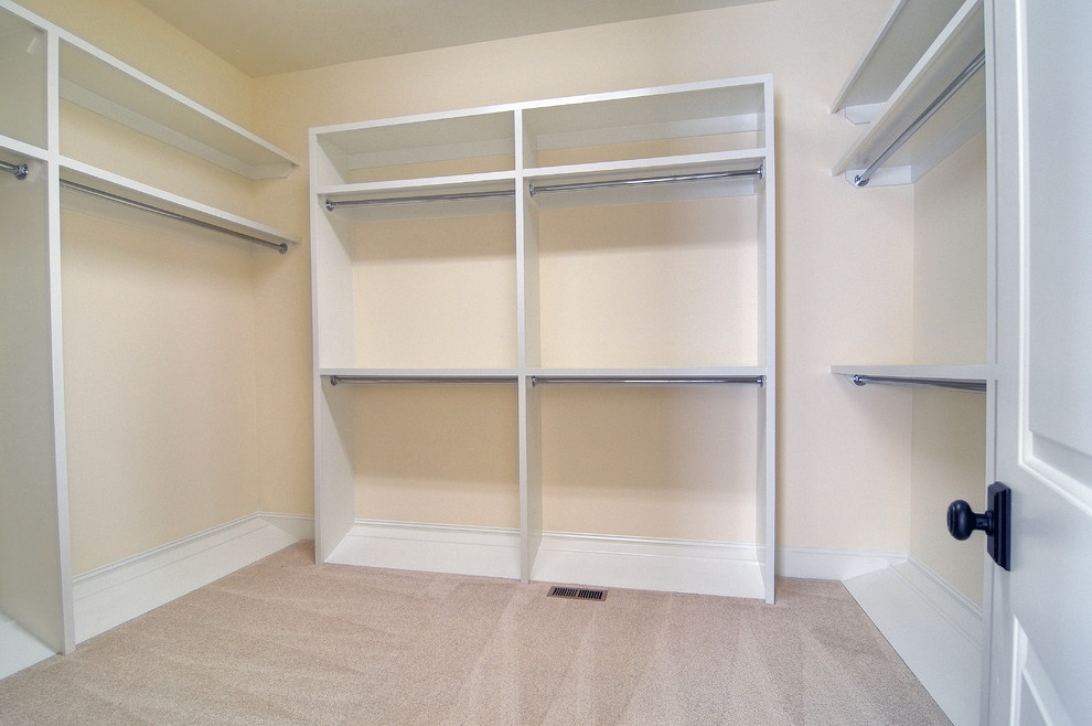This is an example of a gender neutral walk-in wardrobe in Charlotte with white cabinets and carpet.