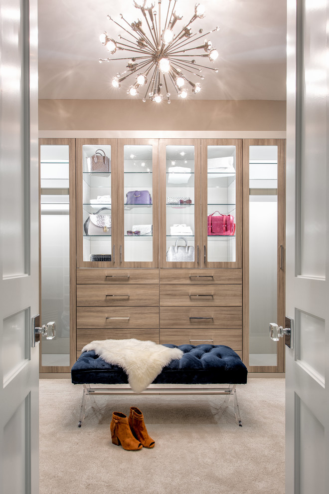 Photo of a traditional gender neutral walk-in wardrobe in Charlotte with flat-panel cabinets, medium wood cabinets, carpet and white floors.