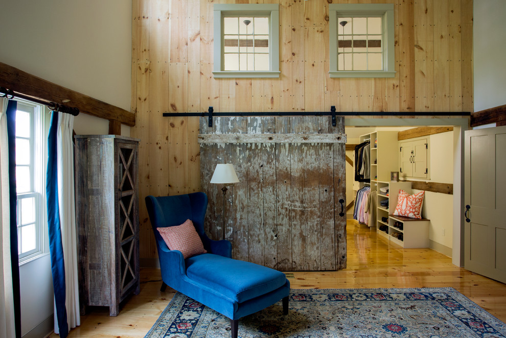 Imagen de vestidor unisex campestre grande con suelo de madera en tonos medios, armarios abiertos y puertas de armario beige