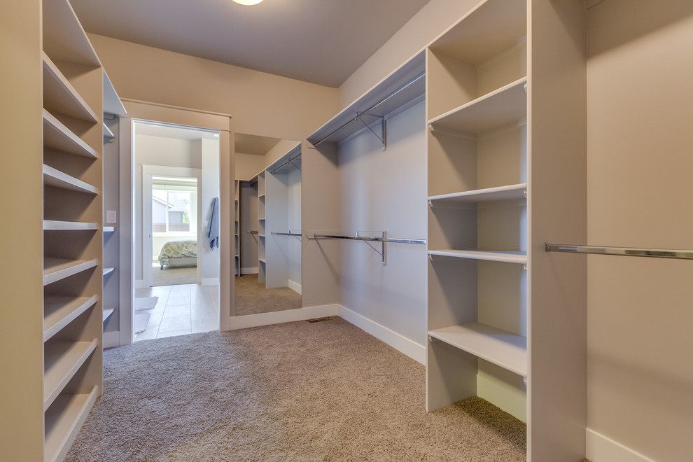 Inspiration for a large contemporary gender neutral walk-in wardrobe in Boise with white cabinets and carpet.